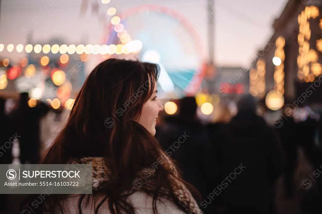 Rear view of happy teenage girl walking in Christmas market in city