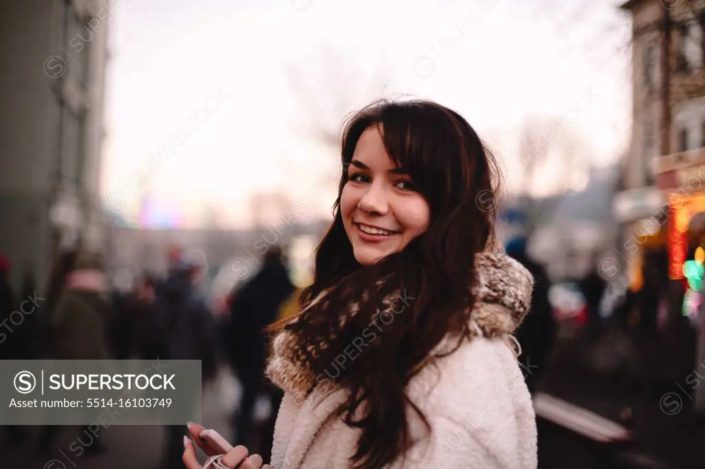 Portrait of happy teenage girl in warm clothing standing in city