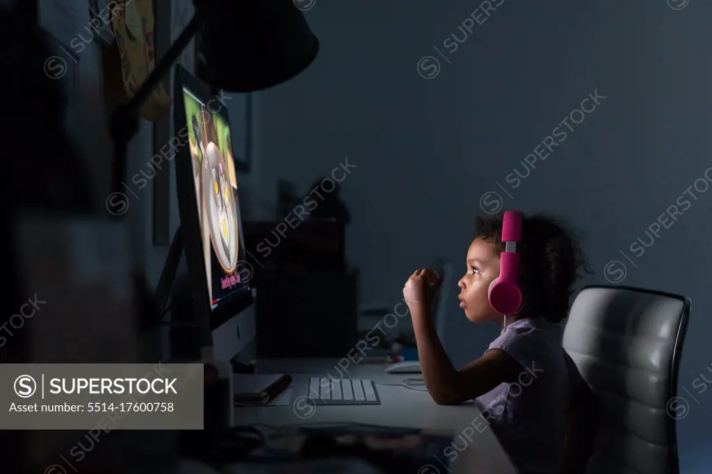 Young girl with headphones using computer at home