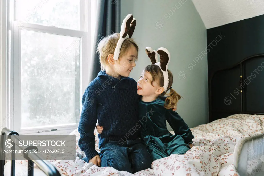 Two kids together in a room talking about reindeers and Santa clause