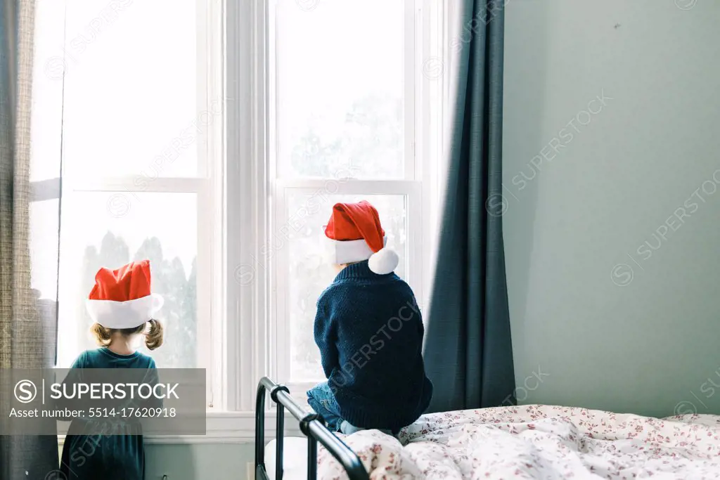 Two children looking through their window waiting for Santa clause