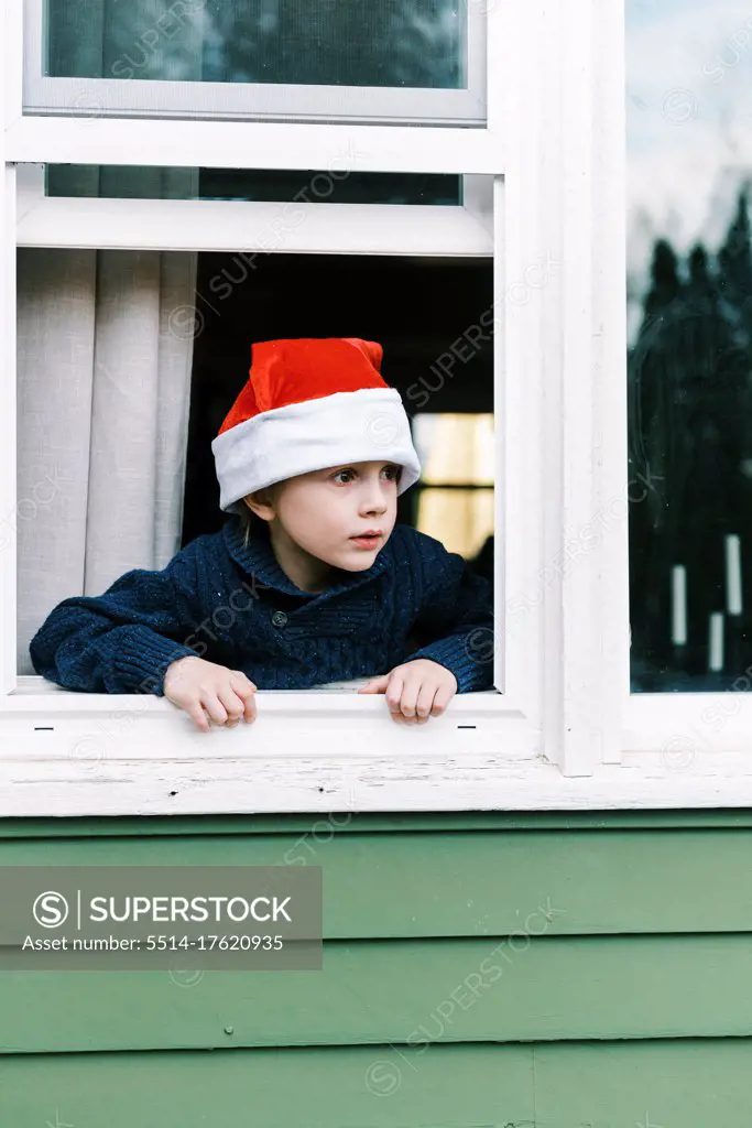 Little boy looking out window waiting for Santa clause on Christmas