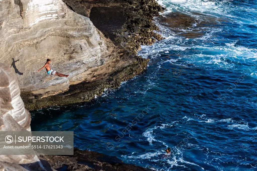 Male cliff diver dives towards the ocean in oahu, hawaii