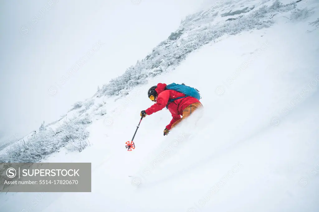 Man skiing in deep snow in the alpine during a snowstorm in Maine