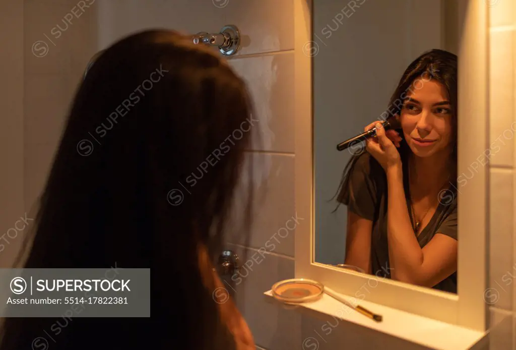 Young female doing makeup in bathroom