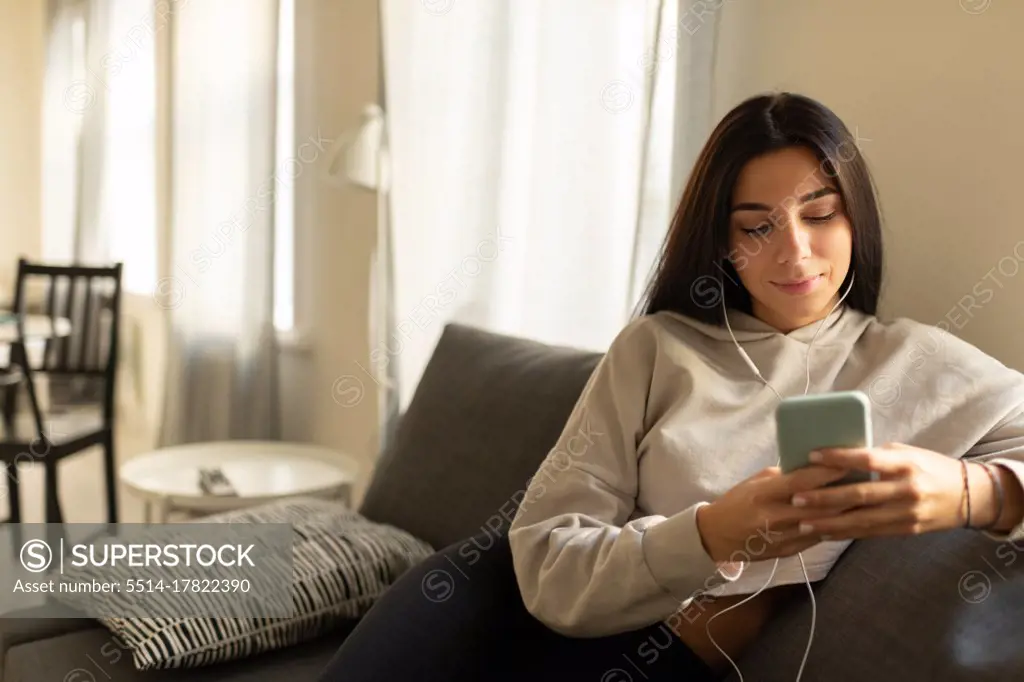Content casual woman in earphones enjoying music at home