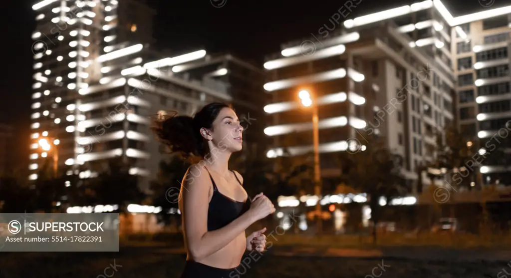 Young sporty female running at night