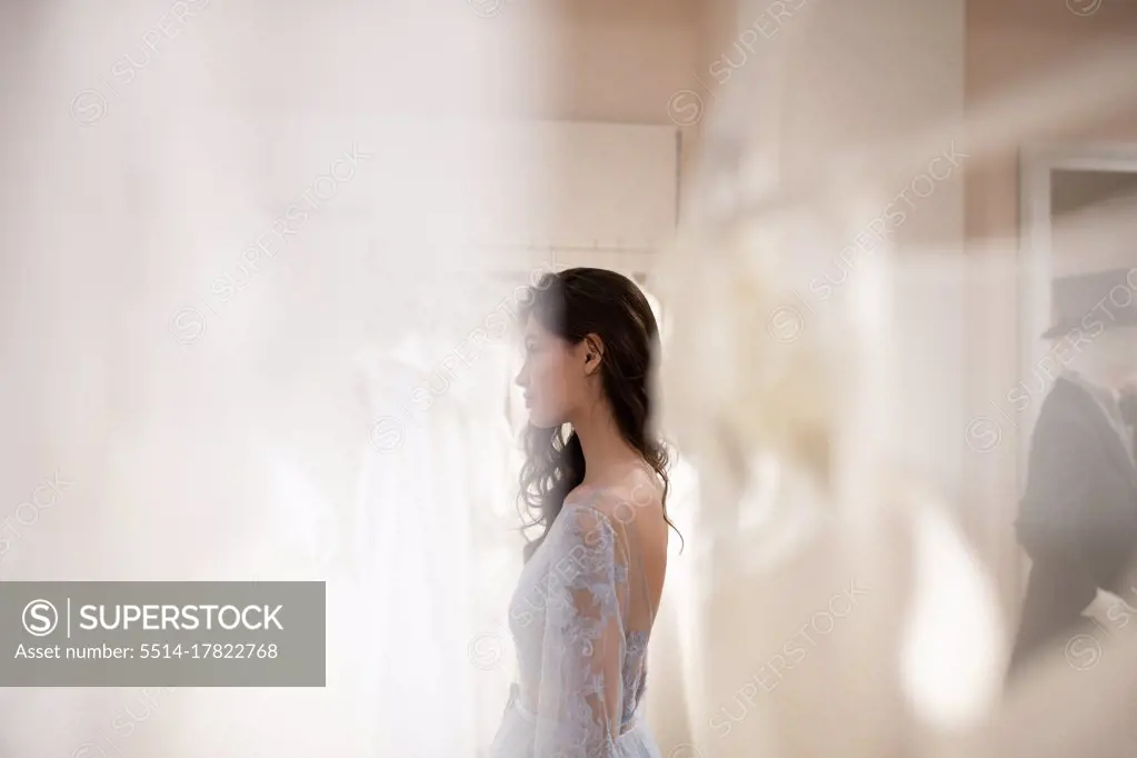 Young woman trying on dress in wedding dress shop