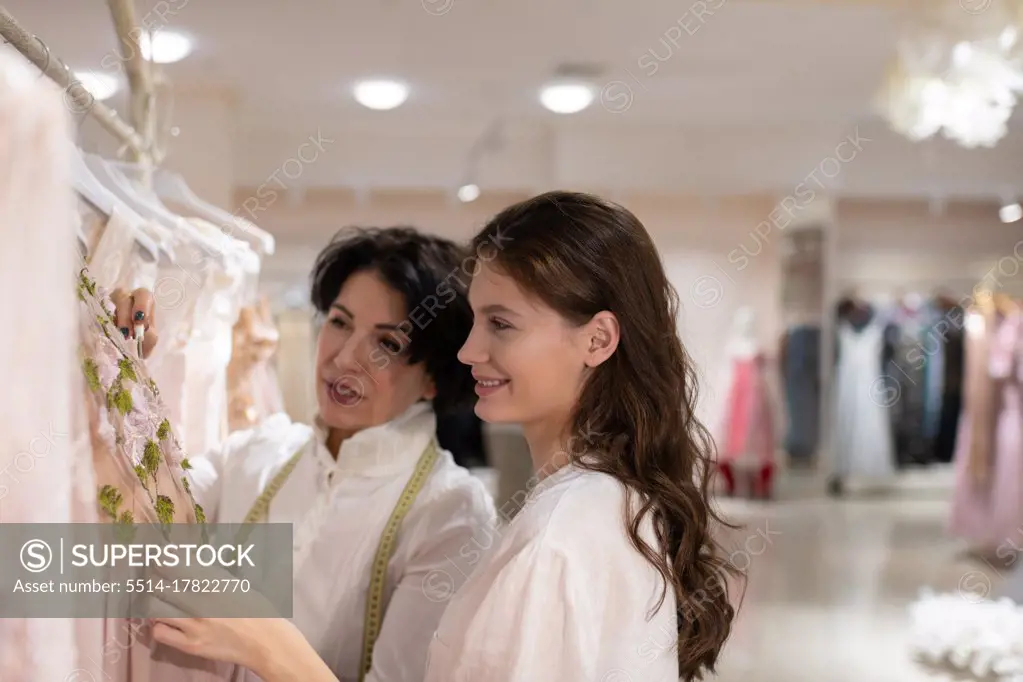 Female customer choosing outfit with help of shop assistant