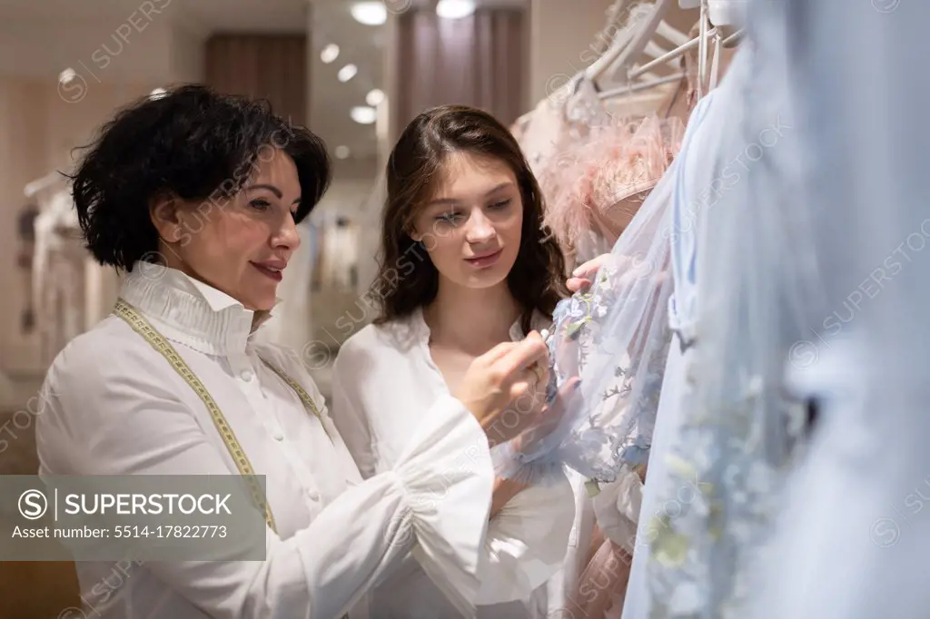 Atelier owner helping client in choosing dress