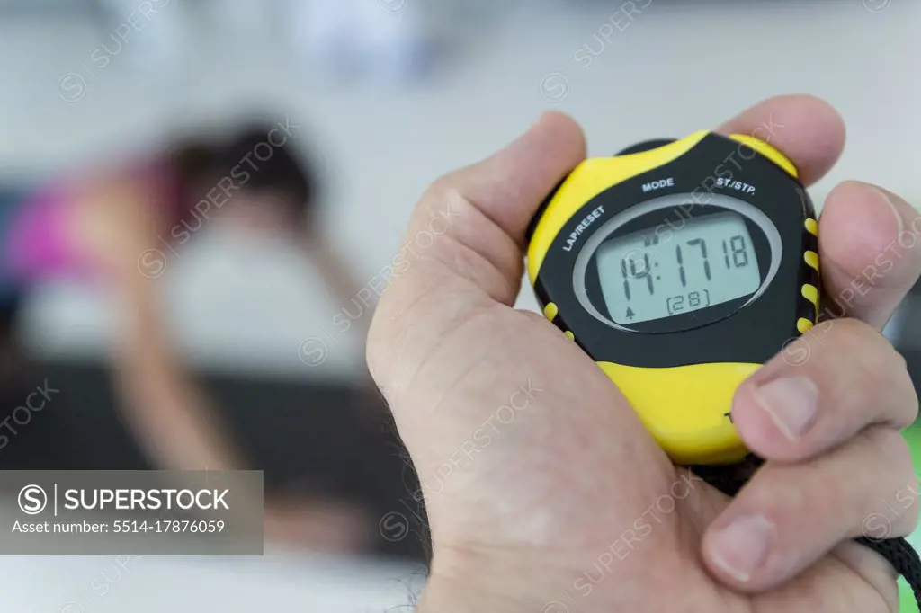 a physical trainer times a physical test, a stopwatch in hand