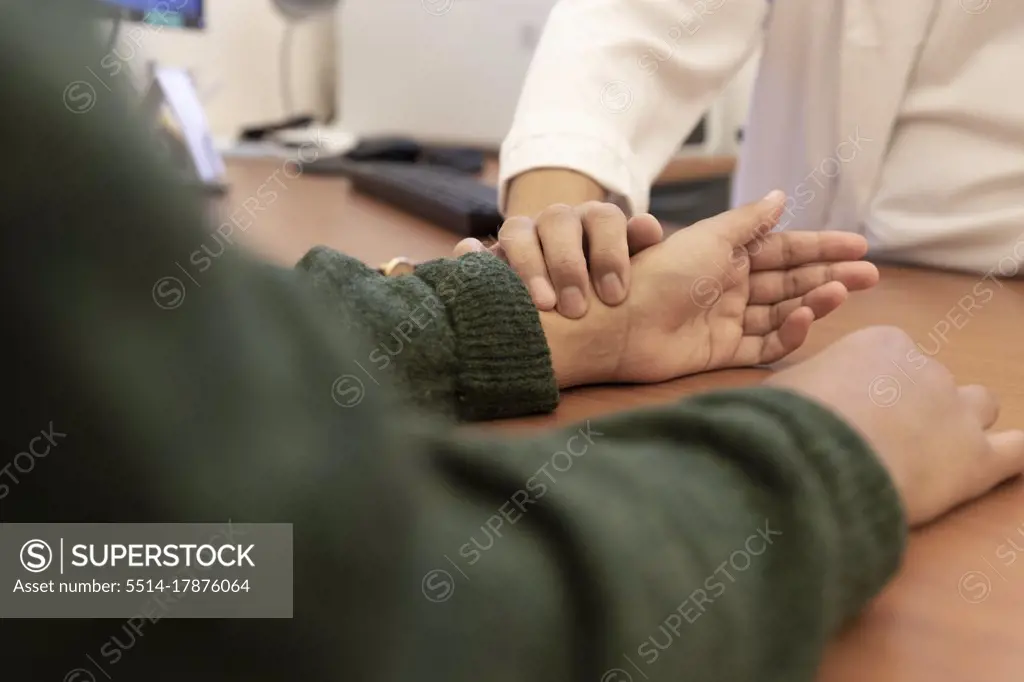 a doctor takes a patient's pulse on the wrist