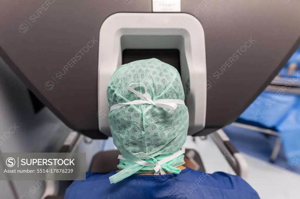 a surgeon is in front of the controls of a robot in the operating room
