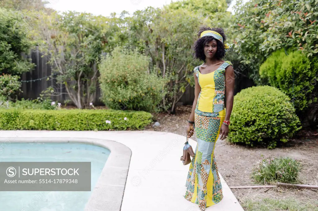 looking camera woman wearing African dress by pool garden