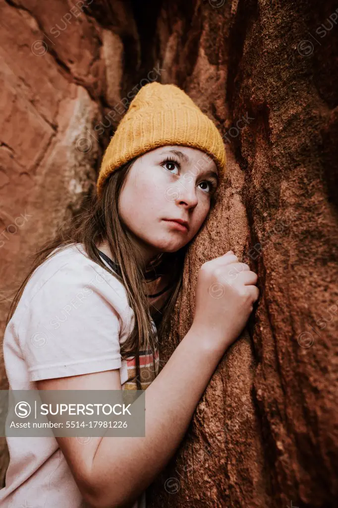 Vertical portrait of preteen girl looking up at rocks