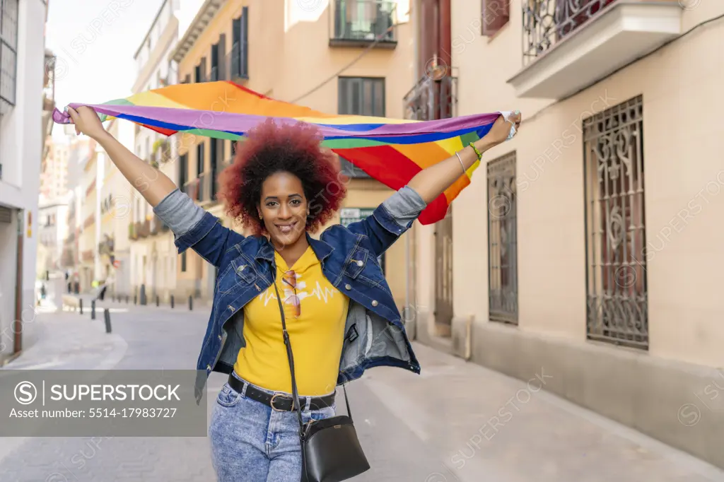 woman with afro hair wearing gay pride flag