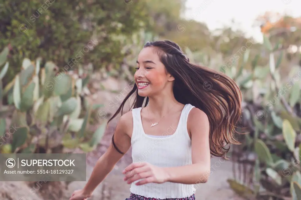 Mixed race girl walking on a cactus trail with her long hair flying.