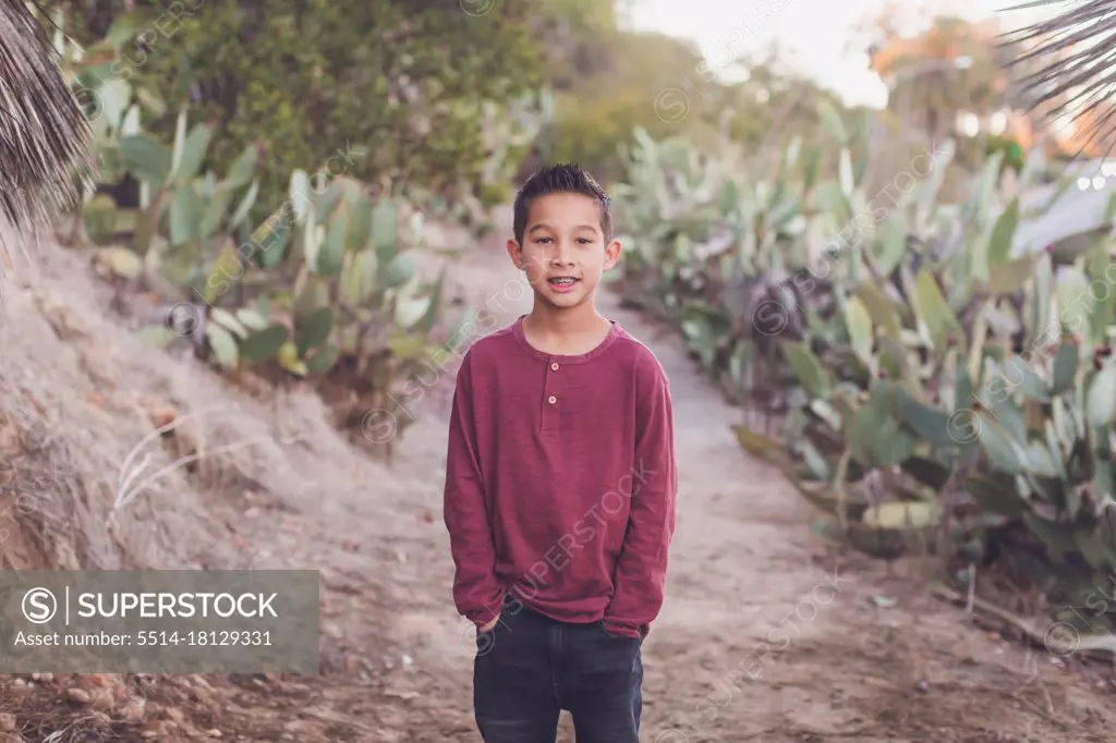 Nine year old boy smiling at the camera, hands in pocket.