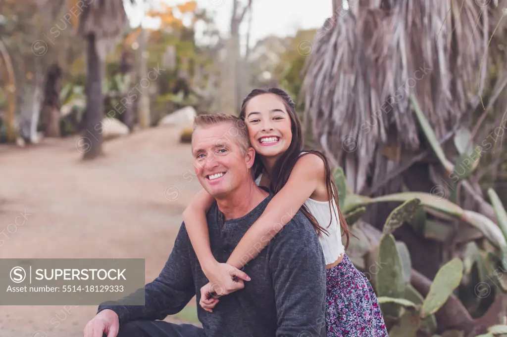 Pre-teen daughter of mixed race hugging her Caucasian father.