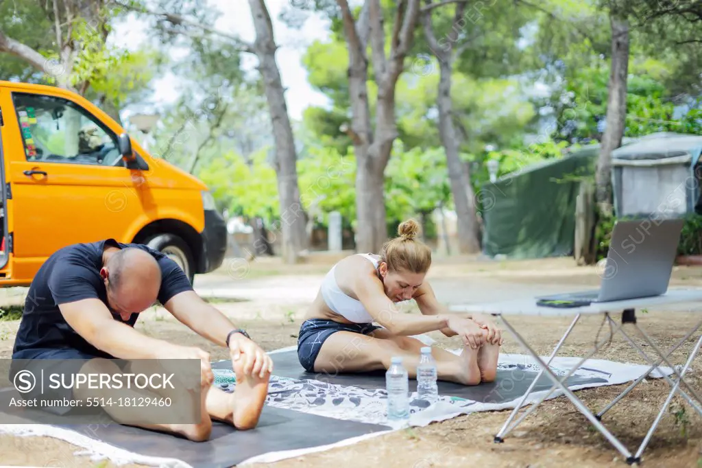 Couple learning yoga online outside