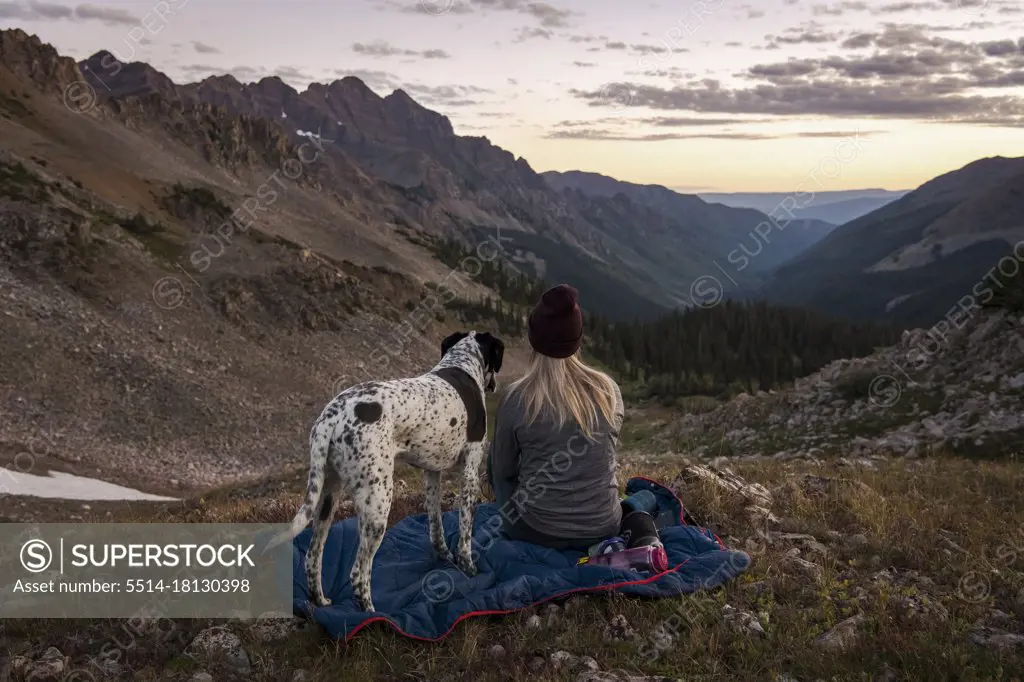 Woman looking at mountains while hiking with dog during sunset