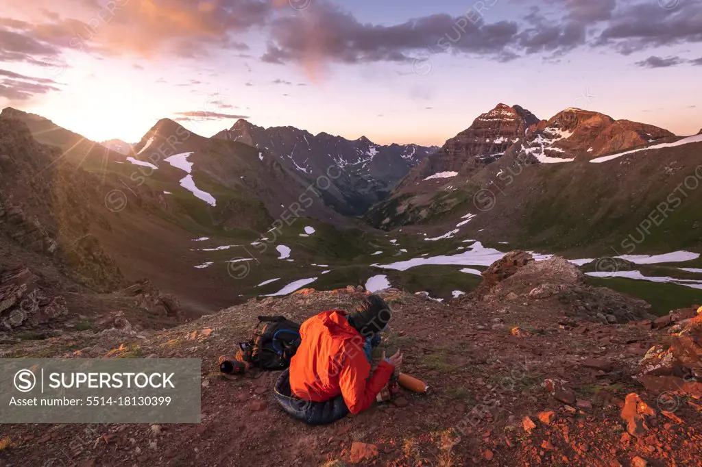 Female hiker sitting on mountain against sky during sunset