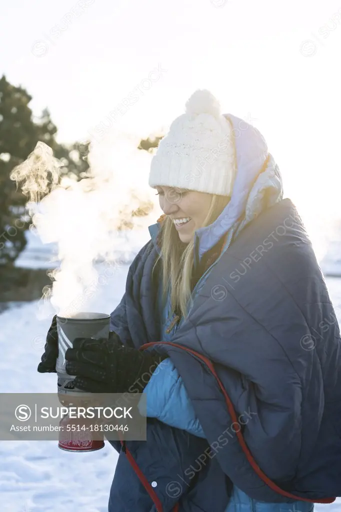 Smiling woman with camping stove during winter