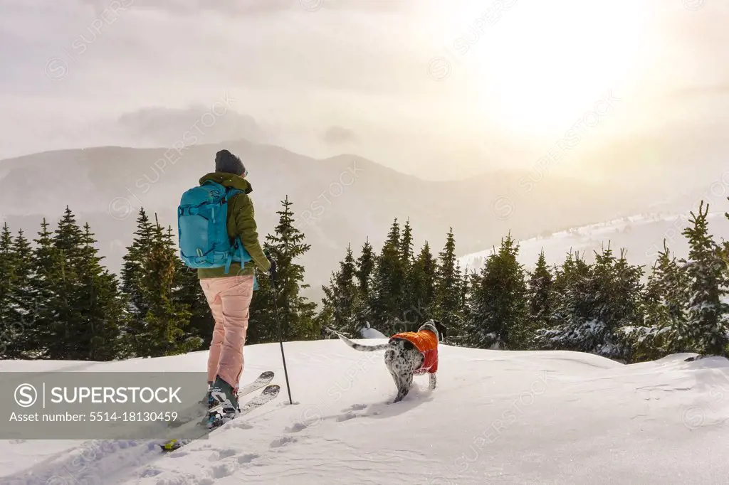 Woman splitboarding by dog against sky during vacation