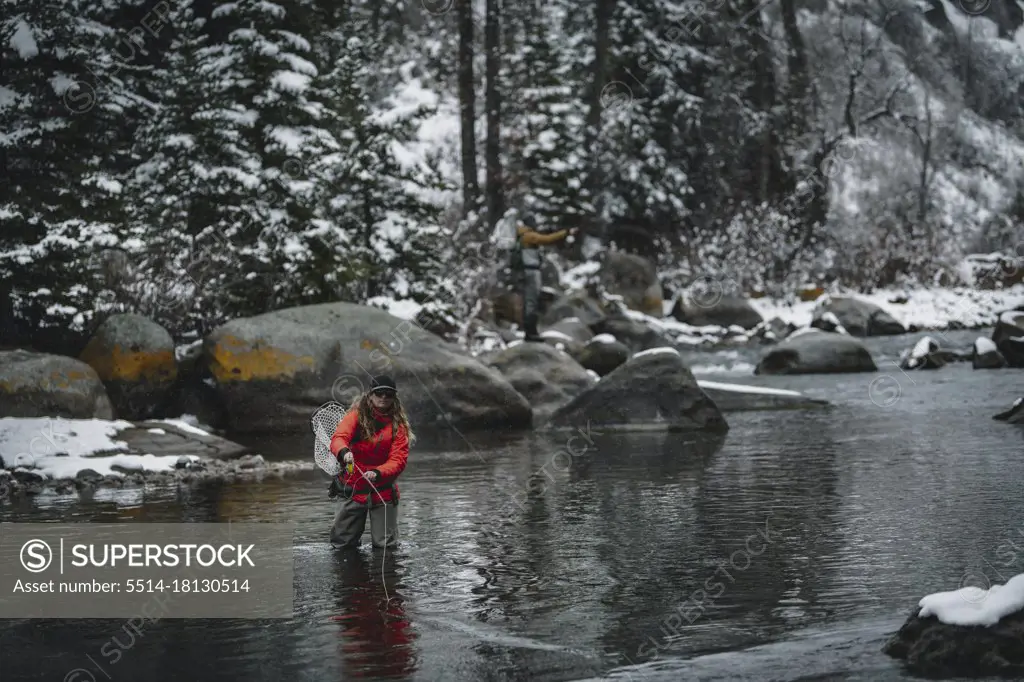 Woman fly fishing while standing in river during winter