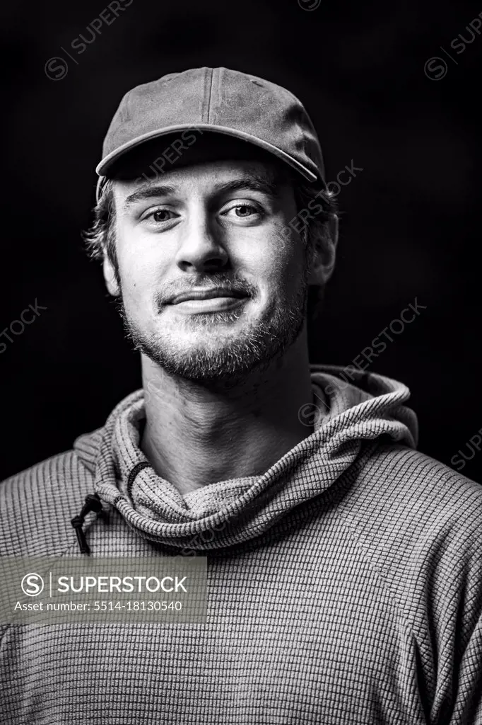 Confident young man in cap against black background