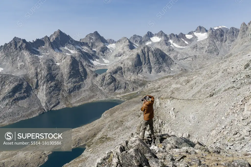 Rear view of man photographing mountains while hiking during vacation