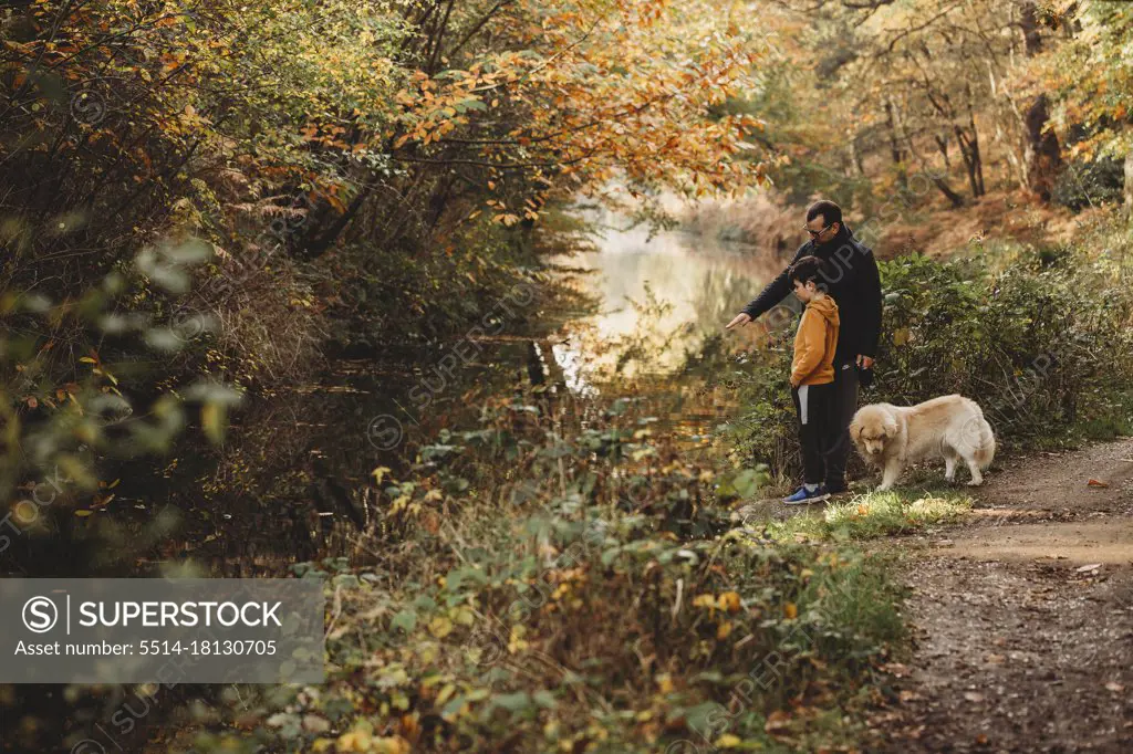Father pointing at canal with son and dog in fall