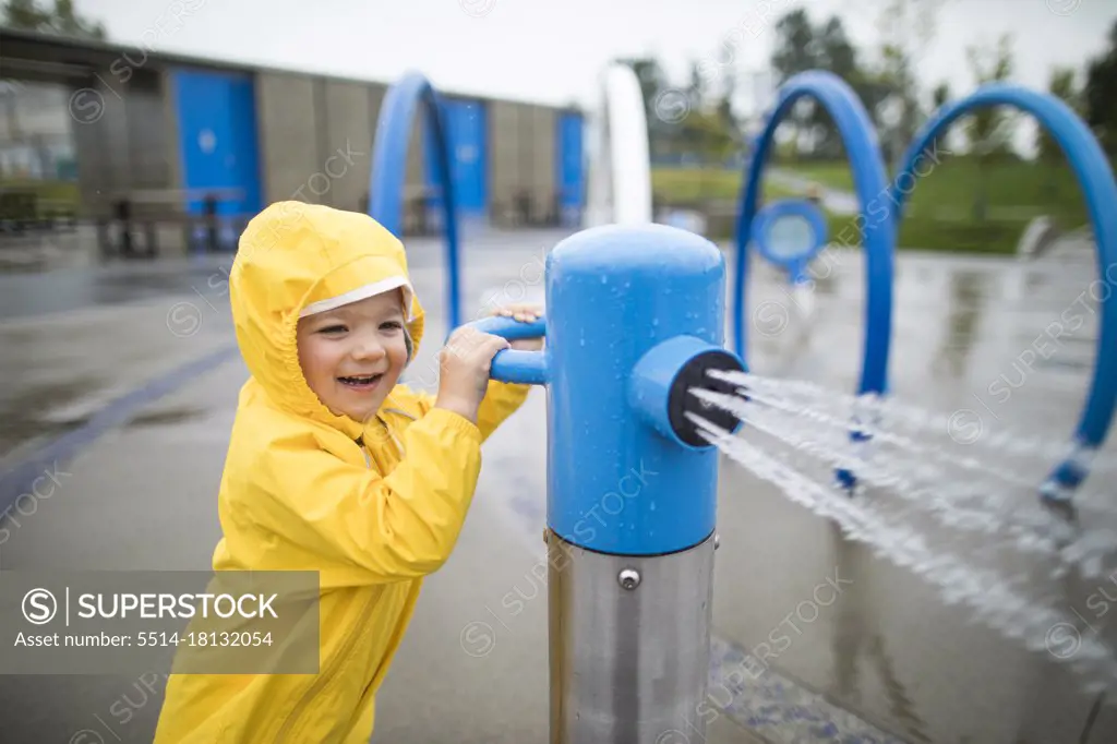 boy plays at the waterpark on a wet day.