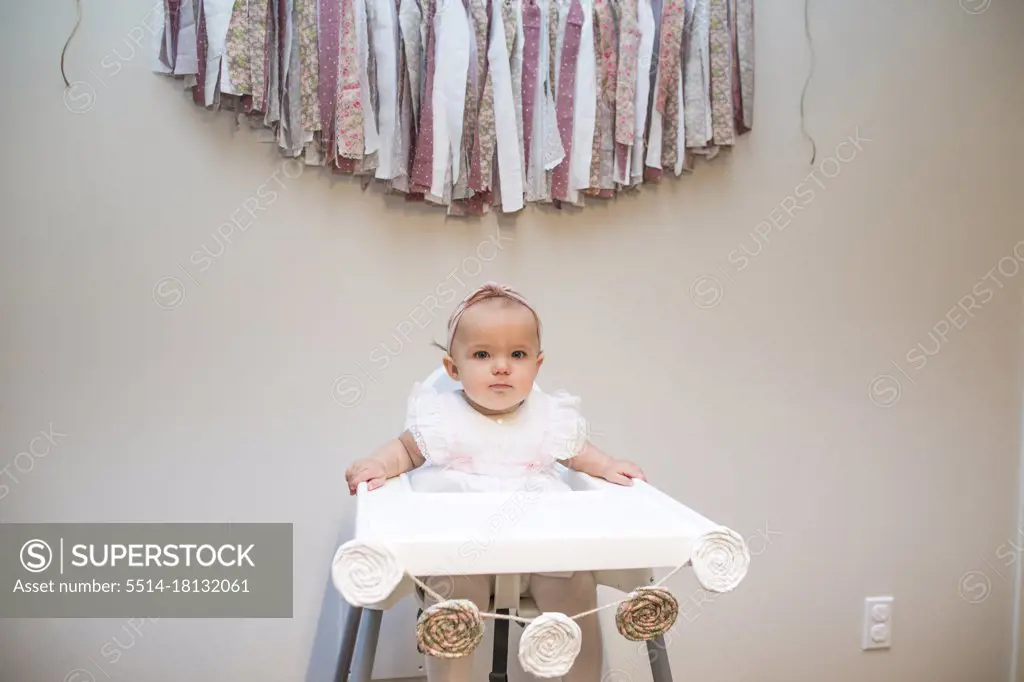First birthday, baby girl sitting under birthday banner