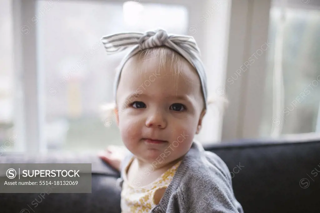Portrait of cute one year old girl wearing headband inside at home