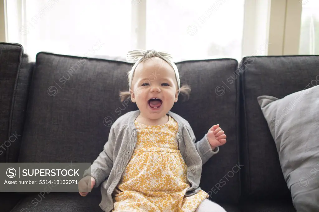 portrait of cute one year old expressive girl sitting on couch