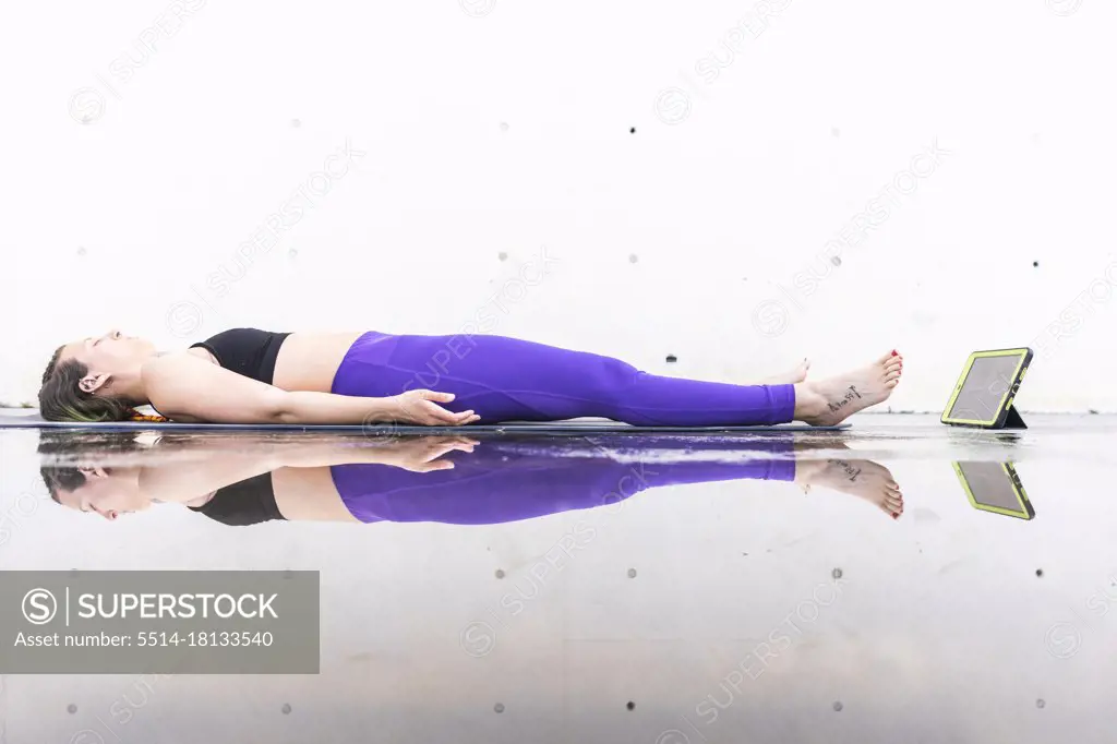 Athlete woman doing the savasana posture during an online yoga class