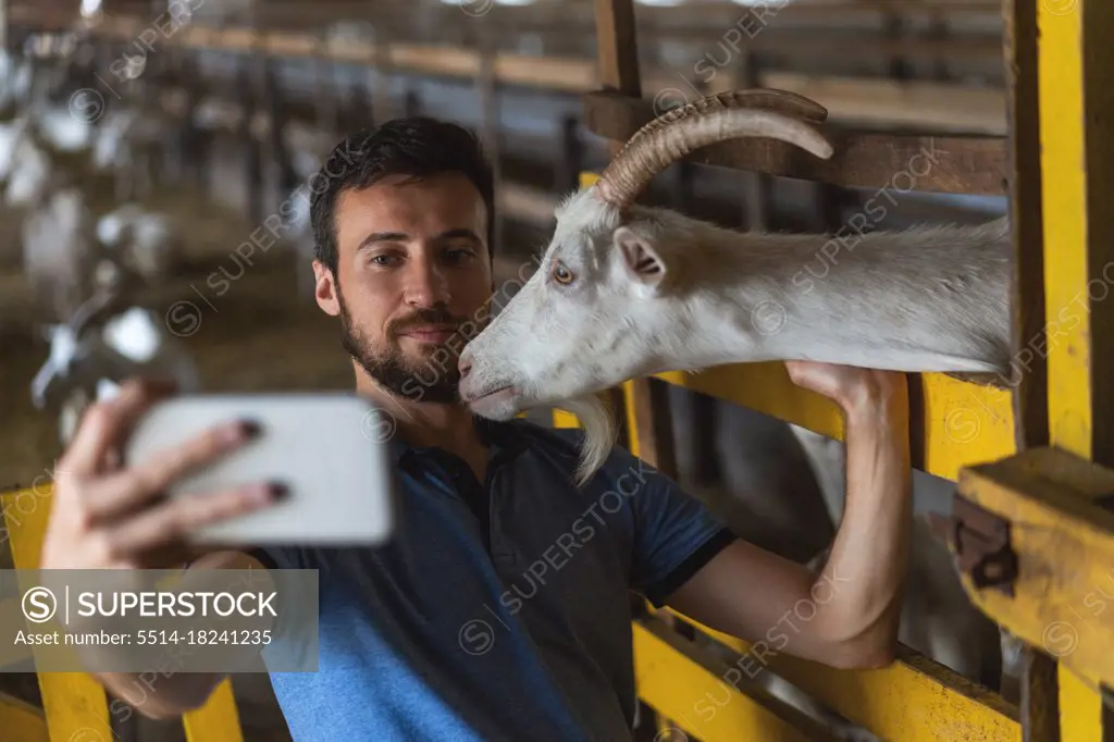 guy takes a selfie on the phone with a goat