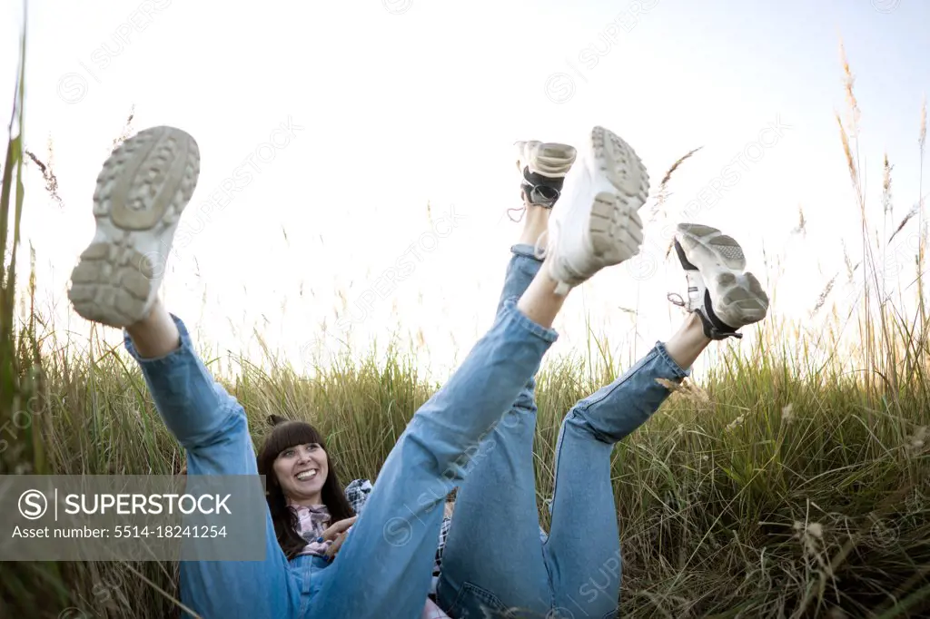Fashion twin girls posing in jeans clothes in the field