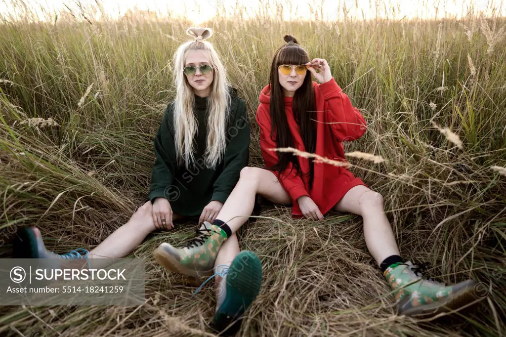 Fashion twin girls posing in bright clothes in the field
