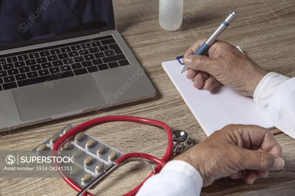 Doctor working with laptop and writing on paper