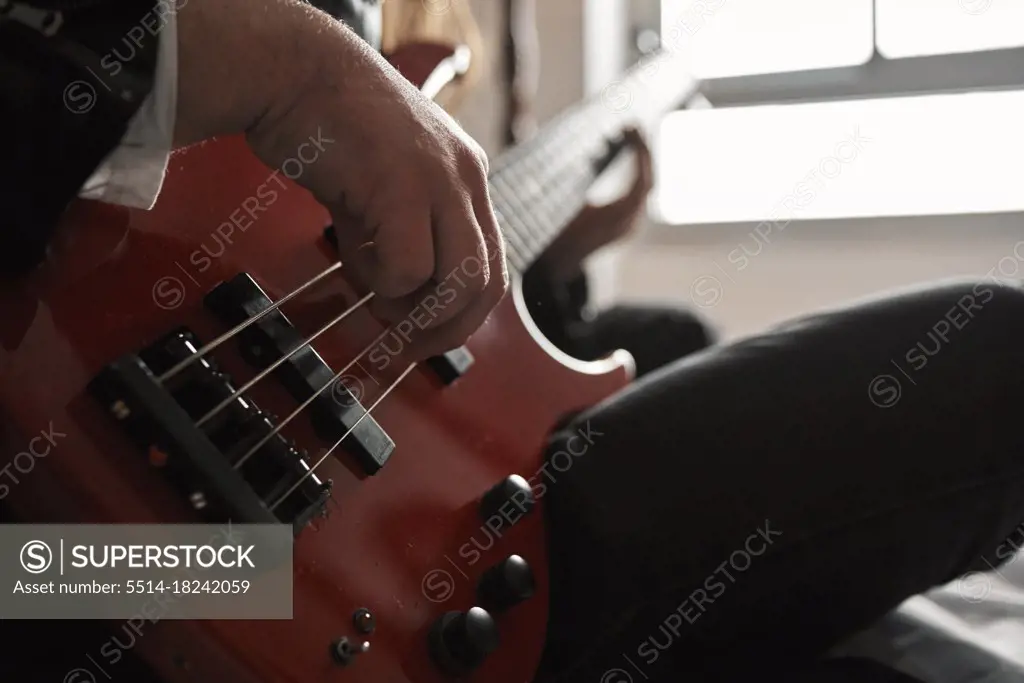 close-up of a man's fingers playing a bass guitar