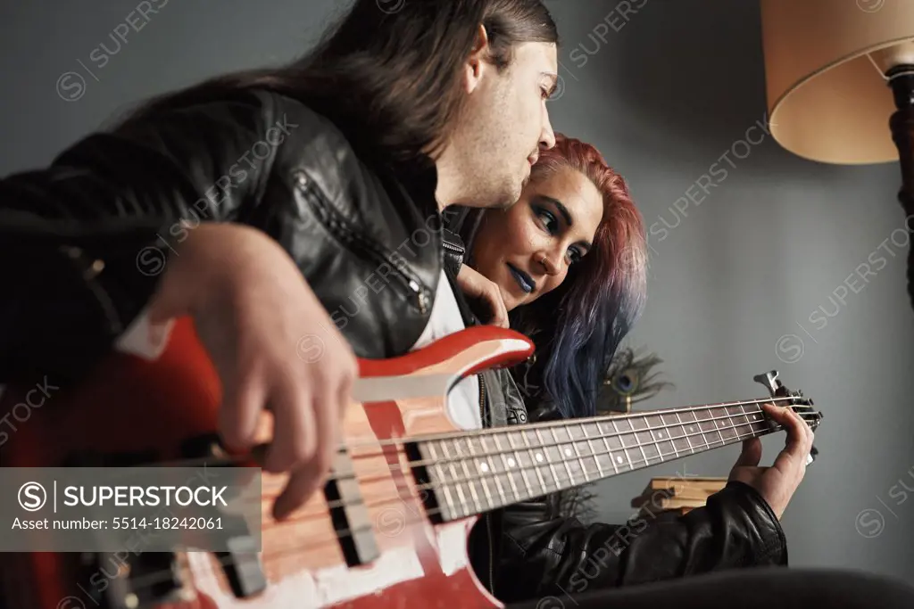 A boy plays bass guitar for his girlfriend