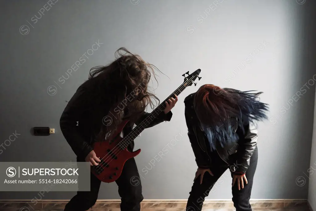 a couple of rockers shake their manes while playing bass guitar