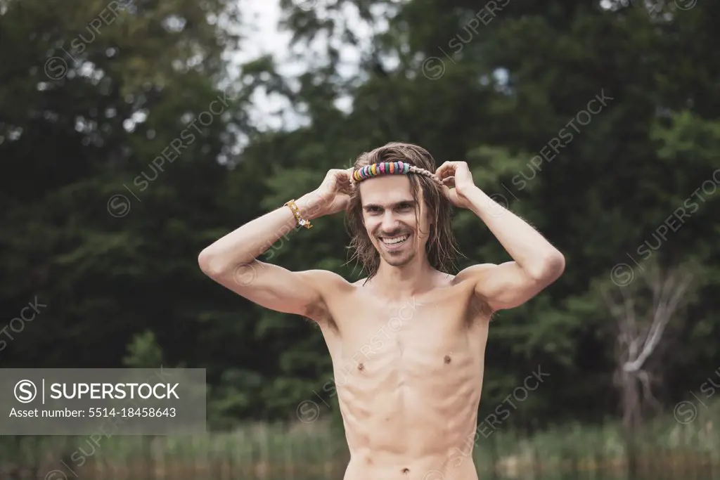Happy healthy man laughs with colourful headband by lake