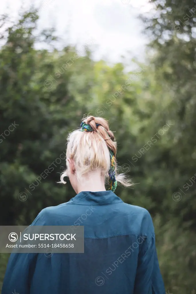 Blond woman with bohemian hairstyle blue shirt walking in forrest