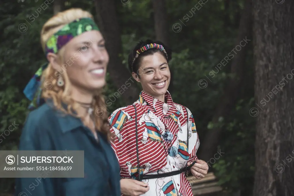 Mixed race women bohemian fashion in forrest together smiling