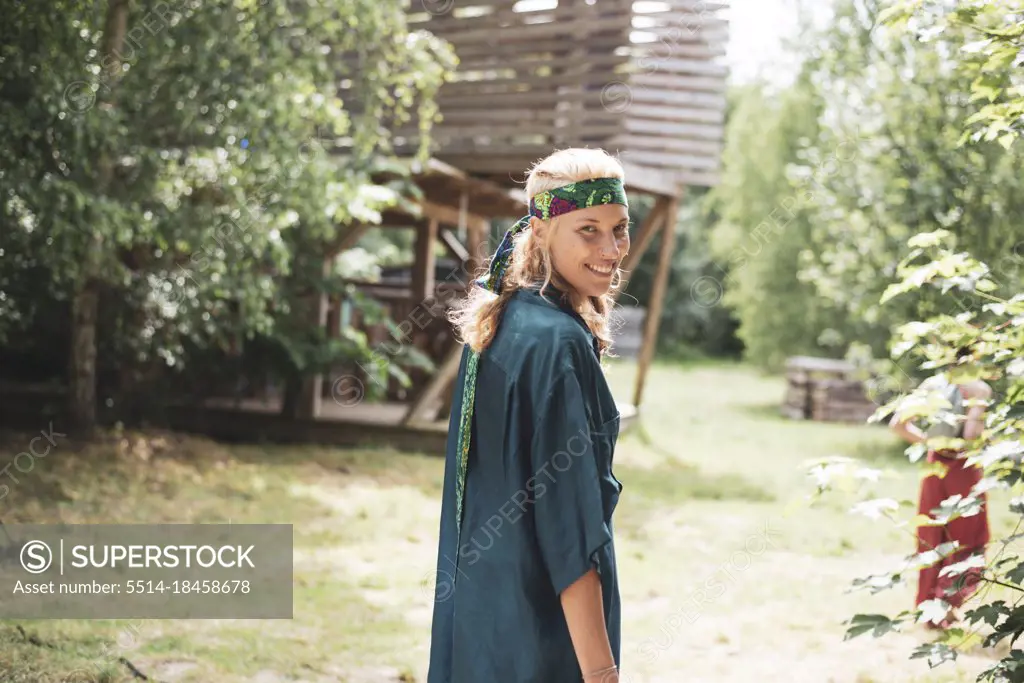 Smiling blond bohemian woman walking in nature at festival in Poland
