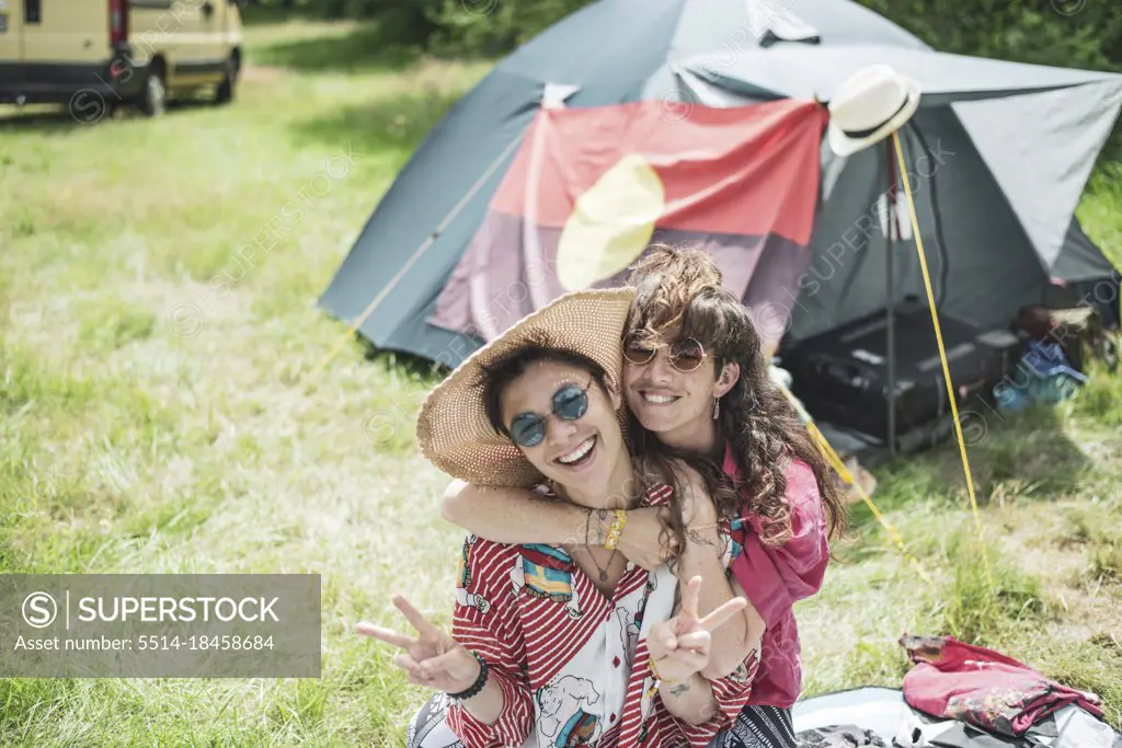 Smiling queer couple in colourful clothes camping at festival