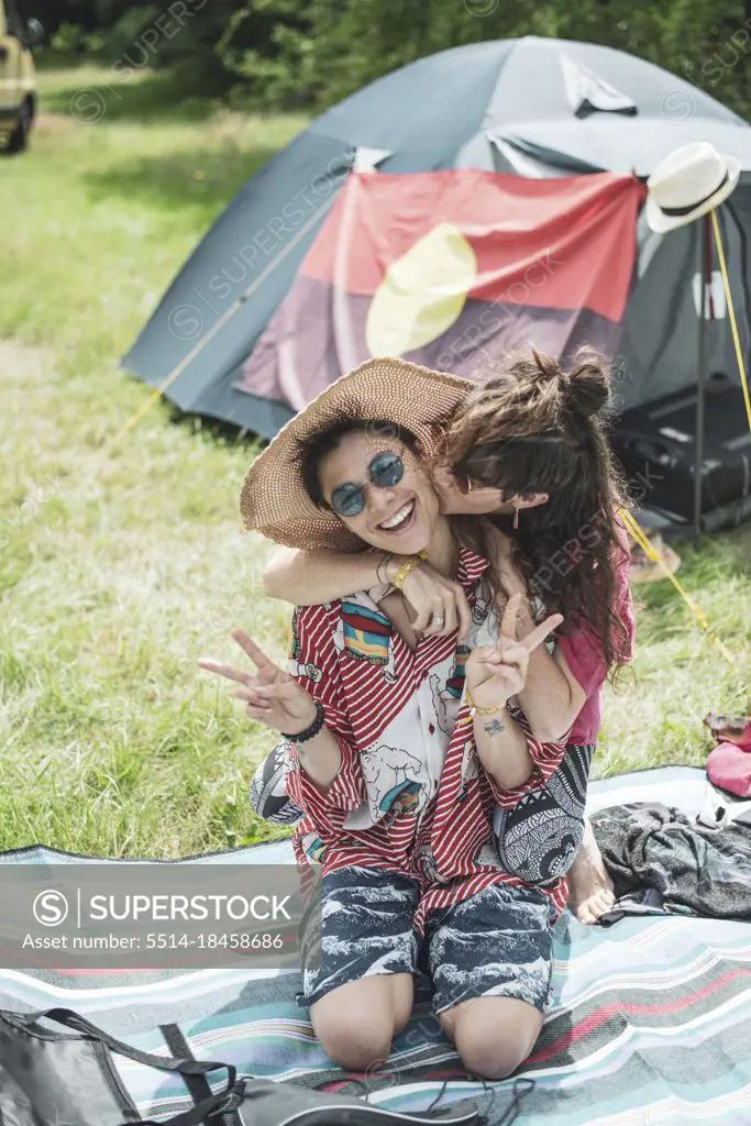 colourful queer female couple hug outside tent in summer camp